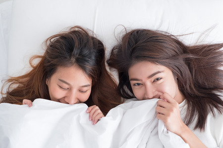 Asia lesbian LGBT Couple lay on bed  cover with blanket and smile with happiness moment together,love win conceptの写真素材