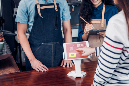 customer self service order drink menu with tablet screen at cafe counter bar,seller coffee shop accept payment by mobile.digital lifestyle conceptの写真素材