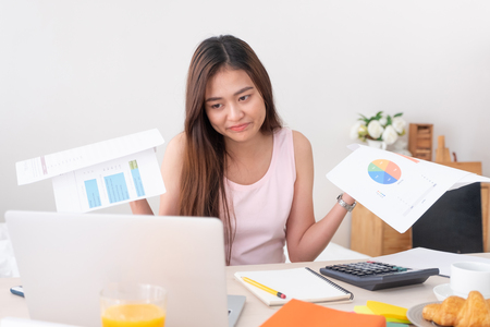 Asian woman freelancer upset with work problem with laptop on mess table.work at home concept.stress workingの写真素材