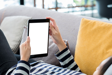 Woman  lying down on sofa using tablet and listening music at home.Mock up screen for display of design or contentの写真素材