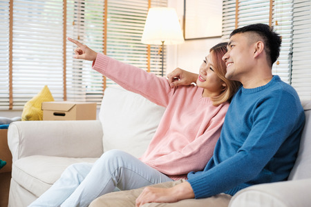 Asian couple planning to decorate house after moving to new home,sitting on sofa with relax emotionの写真素材