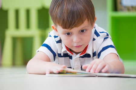 boy kid lay down on floor and reading tale book  in preschool library,Kindergarten school education conceptの写真素材