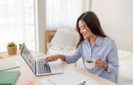 Asian female freelancer drink coffee and and working on laptop at home.Work at home concept.work from home concept.の写真素材