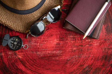 Set of passport ,notebook,sunglasses,compass and white pencil on rustic red wood round table near window.Tropical Summer Holiday vacation conceptの写真素材