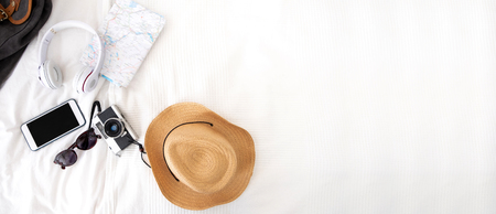 Summer travel items on blanket on bed.Top view of accessories travel (camera,hat,headphone,map ) on bed blankket.prepareing for holiday vacation trip.journey planning.banner for display of designの写真素材