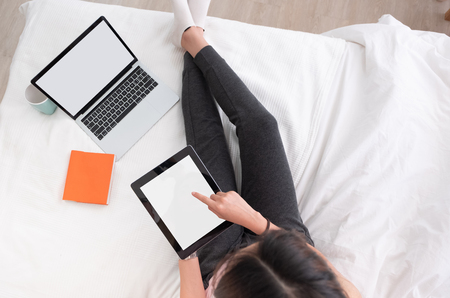 top view woman use tablet,laptp working online on bed in bedroom at home.mock up template device screen.Digital lifestyle concept.clipping pathの写真素材