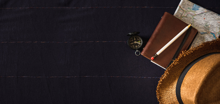 summer vacation item on navy table.Top view of Summer brown panama straw hat,notebook map,compass on linen navy blue cloth.vacation travel concept.banner copy space for adding textの写真素材