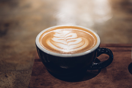 hot coffee cup on table in cafe.Close up hot cappuccino coffee cup with latte art on wood table at cafe,food and drink.の写真素材