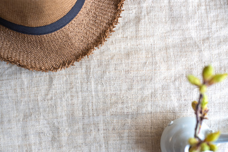 Top view of Summer brown panama straw hat with flower plant in vase on linen cloth.travel concept.copy space for adding text.の写真素材
