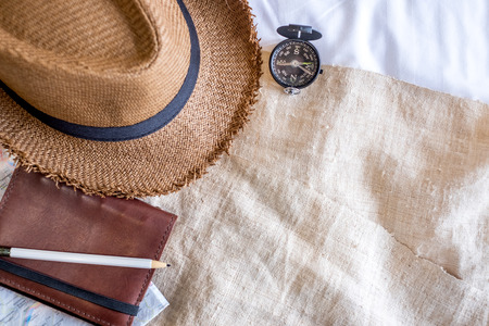 Top view of Summer brown panama straw hat,mobile,notebook map,compass on linen cloth.vacation travel concept.copy space for adding text.の写真素材