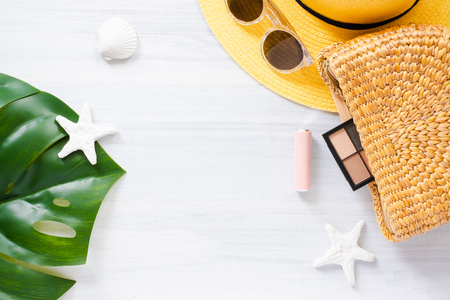 Top view summer item on white wood table.Monstera leaf and wicker bag with cosmetic.summer vacationの写真素材