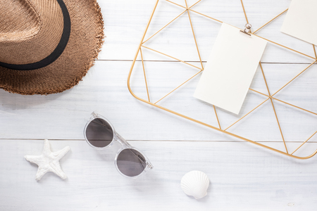 Top view note pad clip frame and summer straw hat with sunglasses on white wood table.summer vacation backgroundの写真素材