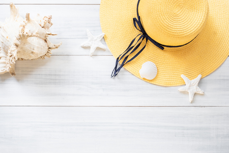 top view of summer yellow female hat with sunglasses and shell and star fish decoration on white wood table.summer vacationの写真素材