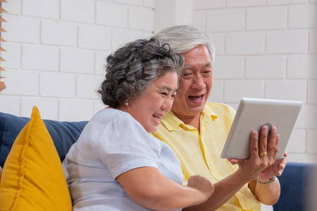 Asian senior couple use tablet video call and talk to grandchild.の写真素材