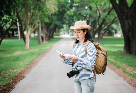 Asian woman backpack traveler use map when traveling at rain forest.Holiday vacation concept.journey lifestyle.solo travel.の写真素材
