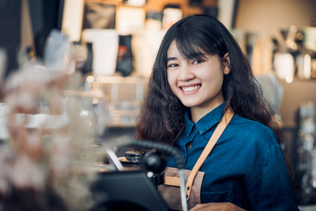 asian woman barista making hot coffee with machine at counter bar and smile at camera in cafe restaurant,Food and drink service concept.の写真素材