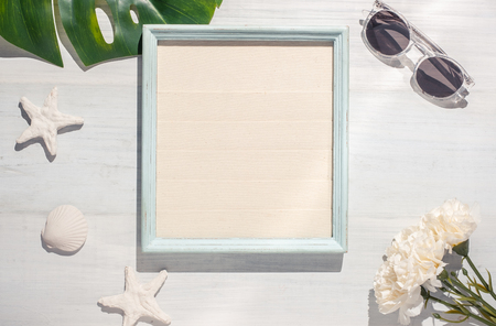 Top view summer picture frame with monstera leaf and seashell on white wood table with hard shadow light.summer vacationの写真素材