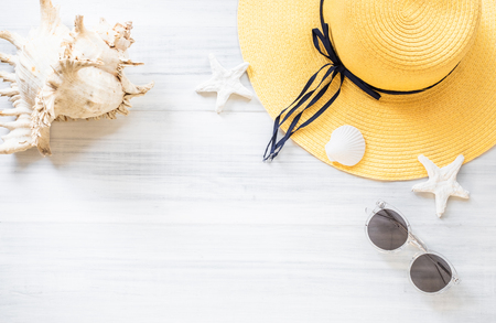 top view of summer yellow female hat with sunglasses and shell and star fish decoration on white wood table.summer vacationの写真素材