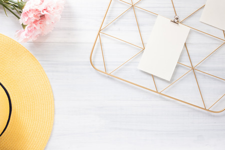 Top view note pad clip frame and summer yellow hat with pink flower on white wood table.summer vacation backgroundの写真素材