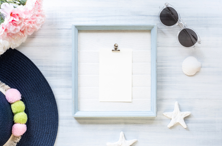 top view of summer blue female hat and picture frame with sunglasses and seashell and star fish decoration on white wood table.summer vacationの写真素材