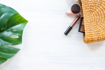 Top view summer item on white wood table.Monstera leaf and wicker bag with cosmetic.summer vacationの写真素材