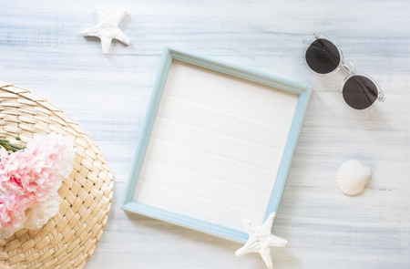 top view of summer blue picture frame with sunglasses and seashell and star fish and pink flower decoration on white wood table.summer vacationの写真素材