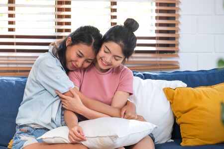 Happy asian lesbian couple hug each other with love on sofa at living room at home,LGBTQ lifestyle conceptの写真素材