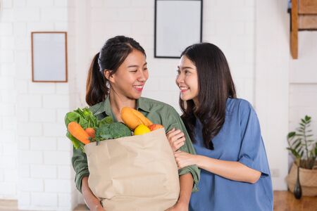 Happy asian couple lesbian holding vegetable bag after shopping at grocery store at home.LGBTQ lifestyle conceptの写真素材