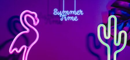 Summer time with pink flamingo, cactus and monstera leaf with neon pink and blue light.Vacation banner mock up space for adding textの写真素材