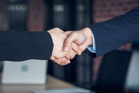 Close up handshake between businesswoman and businessman at meeting room in modern office
