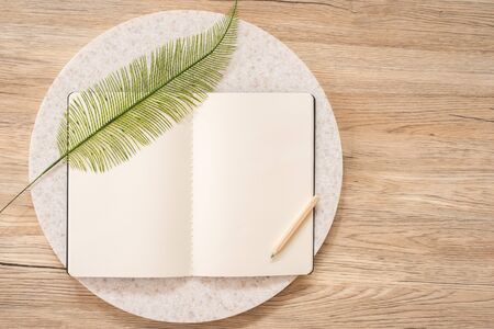 top view of open notebook with leaf and pencil on wooden table with copy space.eco sustainable...