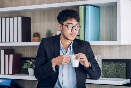 Asian businessman drink coffee at office.take a breake from hard work with relax emotionの写真素材