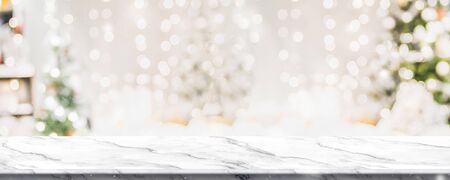 Christmas background of marble table top with abstract warm living room decor with christmas tree string light blur bokeh with snow,Holiday backdrop, panoramic Mock up banner for display of productの写真素材