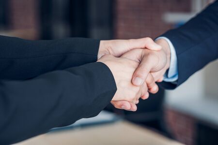 Close up two handshake between businesswoman and businessman at meeting room in modern officeの写真素材