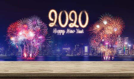 Happy new year 2020 fireworks over cityscape at night with empty wood plank table top,Banner mock up template for display or montage of product for holiday promotion advertisingの写真素材