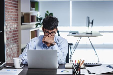 asian businessman woking with laptop and paper work on desk  at office.digital workflow online business lifestyle conceptの写真素材