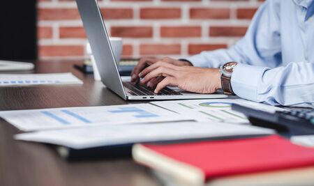asian businessman woking with laptop and paper work on desk  at office.digital workflow online business lifestyle conceptの写真素材