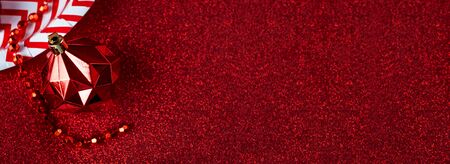 Merry christmas and happy new year red background.top view of tinsel,gift box,ball,ribbon decorate on sparkling table.holiday celebration greeting card.banner panoramic mockup for display of designの写真素材