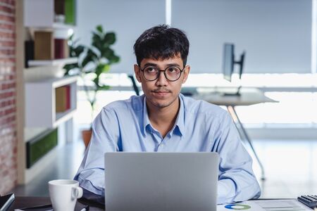 asian businessman woking with laptop and paper work on desk  at office.digital workflow online business lifestyle conceptの写真素材