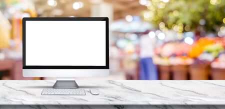 Blank screen desktop computer on marble table top with blur people shopping at supermarket bokeh background,Mock up for display or montage of designの写真素材