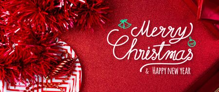 Merry christmas and happy new year red text background.top view of tinsel,gift box,ball,ribbon decorate on sparkling table.holiday celebration greeting card.banner panoramic mockup for display of designの写真素材
