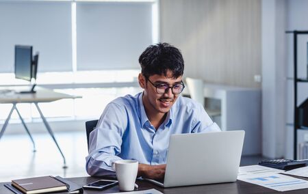 asian businessman woking with laptop and paper work on desk  at office.digital workflow online business lifestyle conceptの写真素材