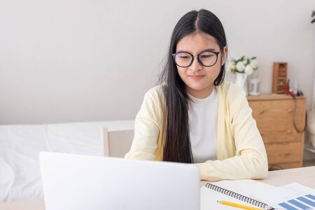 Asian female freelancer working on laptop computer on table at bedroom at home.working online lifestyle.work at home.の写真素材