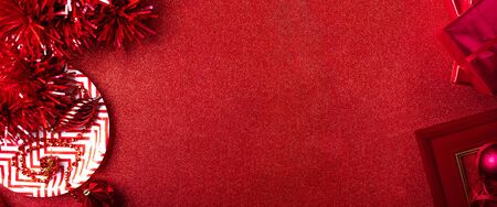 Merry christmas and happy new year red background.top view of tinsel,gift box,ball,ribbon decorate on sparkling table.holiday celebration greeting card.banner panoramic mockup for display of designの写真素材