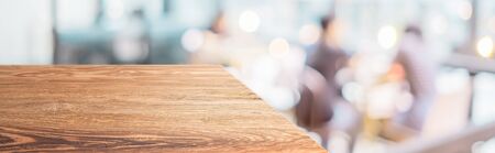 Perspective wood table with blur cafe restaurant with people dining background bokeh light.Panoramic wooden countertop banner mock up for advertising and product display design online contentの写真素材