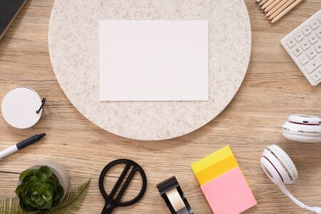 white poster paper mock up on office desk table top view with stationery,notebook,plant on wooden table background.smart phone screen for display of design.business object flat layの写真素材