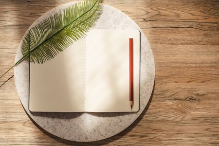 top view of open notebook with leaf and pencil on wooden table with sunlight from window.copy space.eco sustainable conceptの写真素材