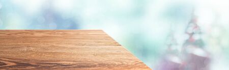 Perspective wood table with blur Christmas tree decorate string light and blue bokeh with snow light.Panoramic wooden countertop banner mock up for product display greeting card design online contentの写真素材