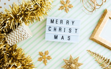 Merry christmas onl lightbox background.top view of sparkling gold tinsel,ball,ornament decorate on green strip line table.holiday celebration greeting cardの写真素材