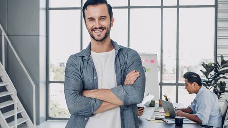portrait of man creative director cross arm smile and looking at camera in modern officeの写真素材